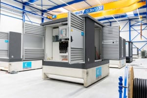 Grote grijze schakelkast met open deuren, waardoor de stroomonderbrekers en bedrading binnenin zichtbaar zijn, gesitueerd in een schone industriële faciliteit - ideaal voor integratie in een moderne Compactstation opstelling.250 kva, 1250 kva trafo, trafo 1250 kva, transformator 1250 kva, trafohuisje 1250 kva