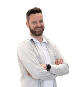 Een man met kort bruin haar en een baard staat met gekruiste armen, draagt een licht overhemd, wit onderhemd en een smartwatch, tegen een effen witte achtergrond-perfect voor je Over ons pagina.