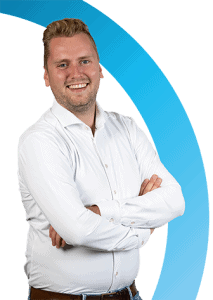 Een man met blond haar, een wit overhemd en een bruine riem staat met gekruiste armen te glimlachen voor een witte achtergrond met een blauwe gebogen streep.