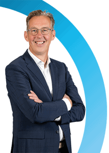 Een man in een marineblauw pak en een bril staat met gekruiste armen te glimlachen voor een witte achtergrond met een blauwe gebogen lijn.