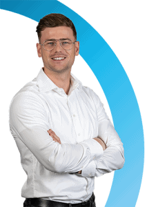 Een man met een bril en een wit overhemd staat met gekruiste armen te glimlachen voor een witte achtergrond met een blauwe gebogen afbeelding.