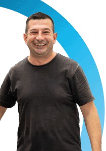 Een man met kort donker haar en een zwart t-shirt staat glimlachend voor een witte achtergrond met een blauwe gebogen lijn, perfect voor een 